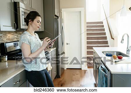 Woman using digital tablet in domestic kitchen View Large Photo Image Stock Image - Woman using digital tablet in domestic kitchen. Fotosearch