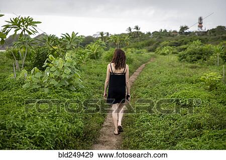 Stock Photo - Woman walking on path through foliage. Fotosearch