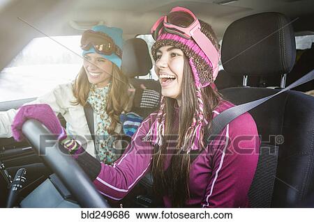 Stock Photograph - Women driving in car in winter and laughing. Fotosearch
