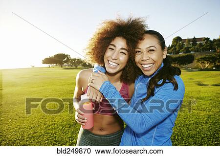 Women hugging and laughing in sunny field View Large Photo Image Stock Image - Women hugging and laughing in sunny field. Fotosearch