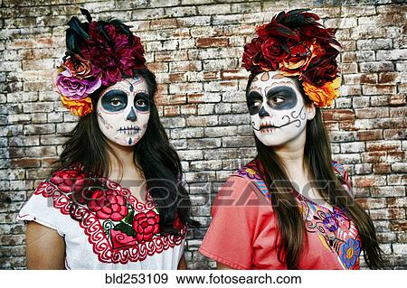Stock Photo - Women near brick wall wearing skull face paint. Fotosearch