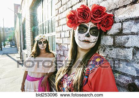Stock Photograph - Women on sidewalk wearing skull face paint. Fotosearch