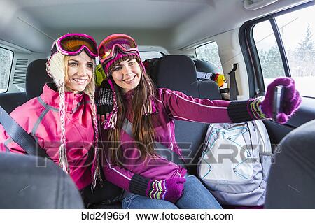Picture - Women posing for cell phone selfie in car in winter. Fotosearch