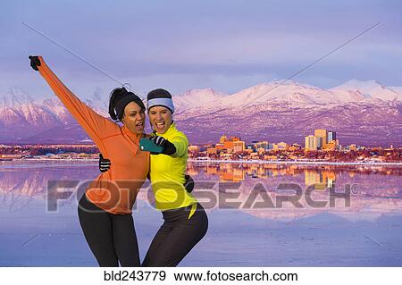 Stock Photo - Women posing for cell phone selfie near mountain river. Fotosearch