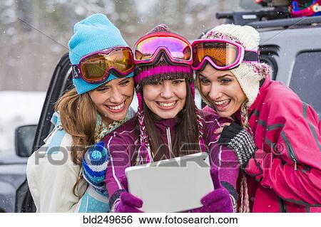 Stock Photograph - Women posing for selfie with digital tablet in winter. Fotosearch