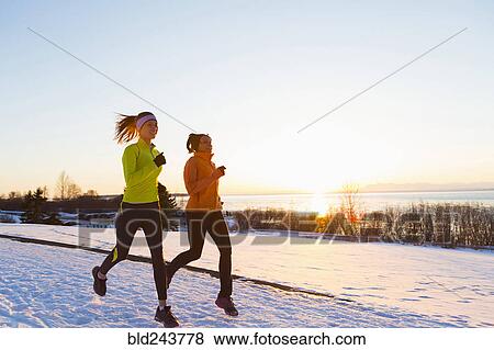 Stock Photo - Women running on snow in winter. Fotosearch