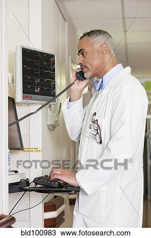 Stock Image - African American doctor talking on telephone in hospital. Fotosearch