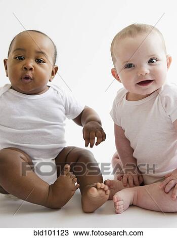 Stock Image - Babies sitting together on floor. Fotosearch
