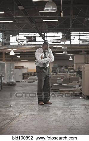 Stock Image - Black businessman standing in warehouse. Fotosearch