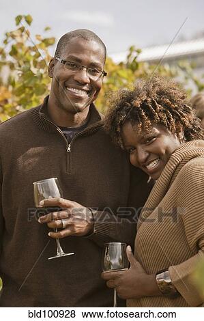 Stock Photo - Black couple drinking wine in vineyard. Fotosearch