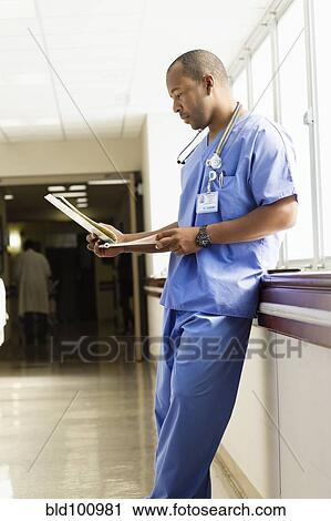 Stock Image - Black doctor looking at medical chart in hospital. Fotosearch