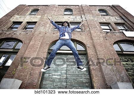 Black man jumping next to urban building View Large Photo Image Stock Image - Black man jumping next to urban building. Fotosearch