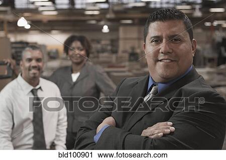 Stock Image - Business people standing in warehouse. Fotosearch