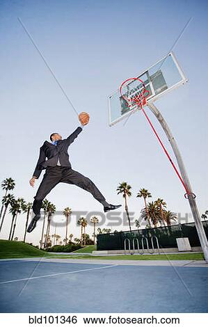 Stock Photograph - Businessman playing basketball outdoors. Fotosearch
