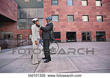 Stock Photography - Businessman putting bicycle helmet on girlfriend. Fotosearch