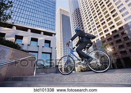 Stock Photo - Businessman riding bicycle in city. Fotosearch