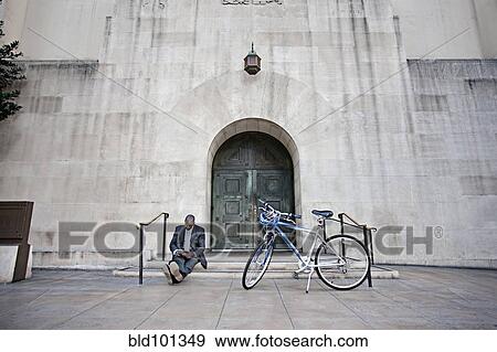 Businessman sitting on steps near bicycle View Large Photo Image Stock Photo - Businessman sitting on steps near bicycle. Fotosearch