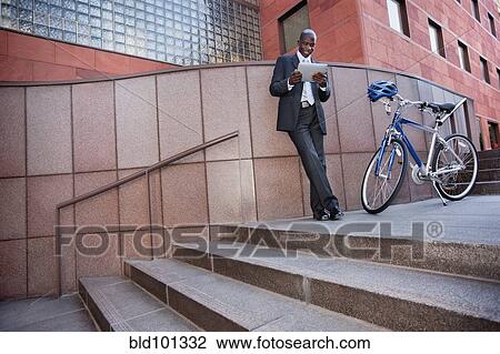 Businessman standing near bicycle using digital tablet View Large Photo Image Stock Image - Businessman standing near bicycle using digital tablet. Fotosearch