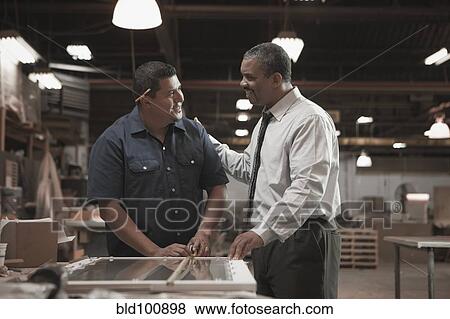 Stock Photo - Businessman talking to worker in warehouse. Fotosearch