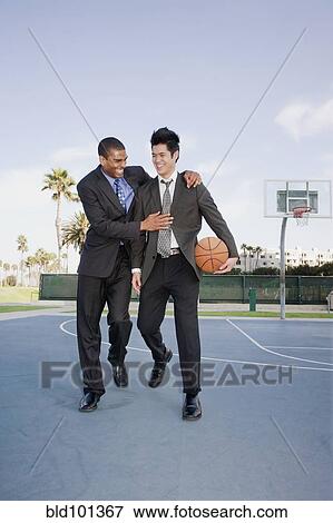 Stock Photo - Businessmen playing basketball outdoors. Fotosearch