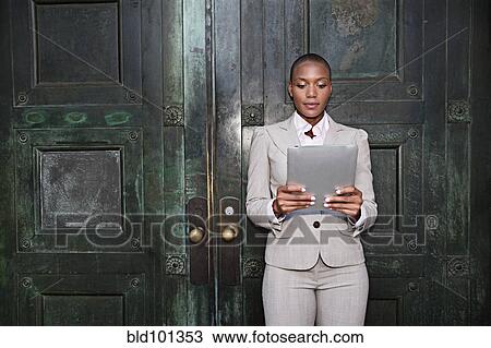 Businesswoman leaning against door using digital tablet View Large Photo Image Stock Image - Businesswoman leaning against door using digital tablet. Fotosearch
