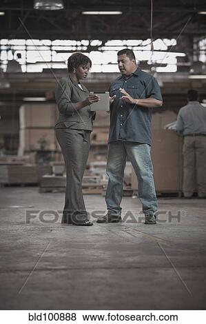 Businesswoman talking to worker in warehouse View Large Photo Image Stock Photo - Businesswoman talking to worker in warehouse. Fotosearch