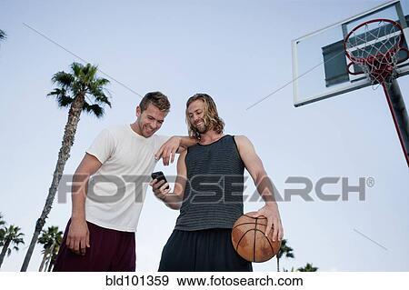 Stock Photo - Caucasian basketball players looking at cell phone. Fotosearch