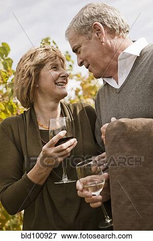 Stock Photo - Caucasian couple drinking wine in vineyard. Fotosearch