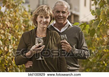 Stock Photo - Caucasian couple drinking wine in vineyard. Fotosearch