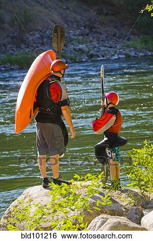 Stock Photograph - Caucasian father and child with kayak near river. Fotosearch