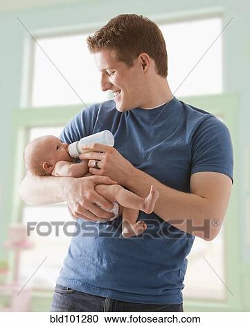 Stock Image - Caucasian father feeding baby girl. Fotosearch
