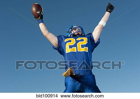 Caucasian football player holding football with arms raised View Large Photo Image Picture - Caucasian football player holding football with arms raised. Fotosearch