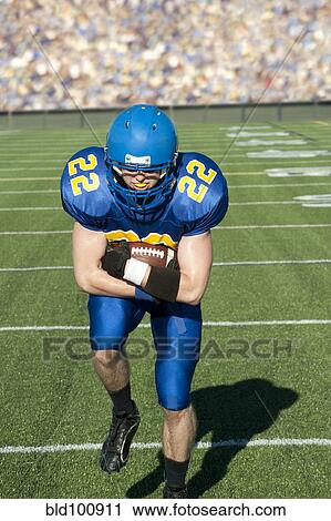 Stock Image - Caucasian football player running with ball. Fotosearch