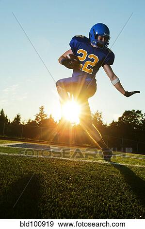 Stock Photo - Caucasian football player running with ball. Fotosearch