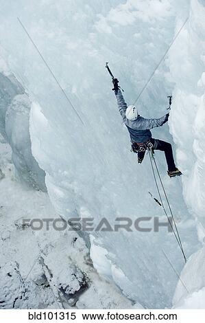 Stock Photography - Caucasian man climbing ice. Fotosearch