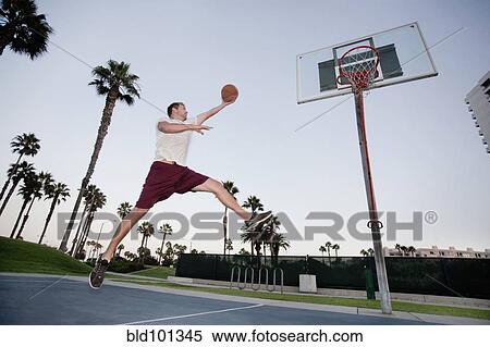 Stock Photography - Caucasian man playing basketball outdoors. Fotosearch