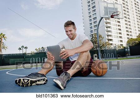 Stock Image - Caucasian man using digital tablet on basketball court. Fotosearch