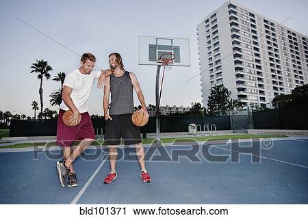 Stock Image - Caucasian men standing on basketball court. Fotosearch