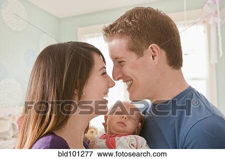 Caucasian mother and father holding baby girl View Large Photo Image Stock Photo - Caucasian mother and father holding baby girl. Fotosearch
