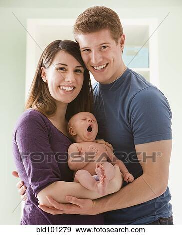 Stock Photo - Caucasian mother and father holding baby girl. Fotosearch