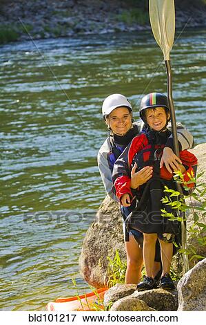Stock Photo - Caucasian mother and son with kayak near river. Fotosearch