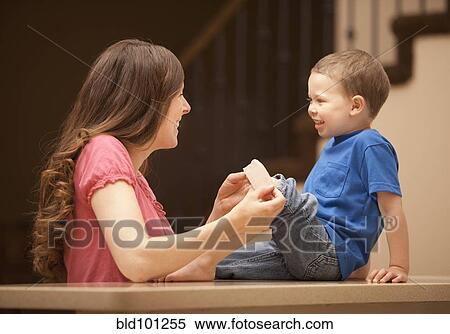 Stock Photography - Caucasian mother putting bandage on son's knee. Fotosearch
