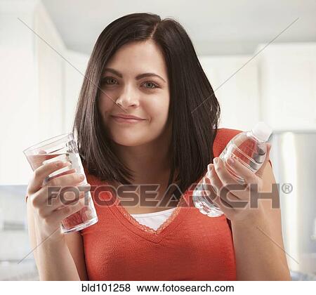 Stock Photo - Caucasian woman holding glass and bottle of water. Fotosearch