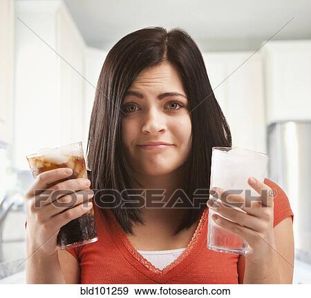 Stock Photo - Caucasian woman holding glasses of soda and water. Fotosearch