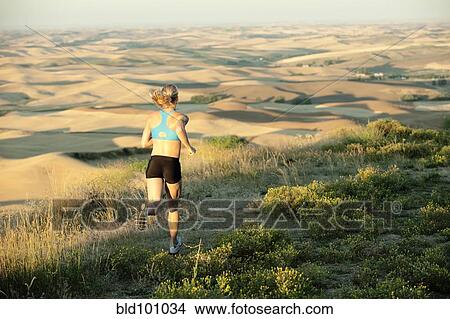 Picture - Caucasian woman running in remote area. Fotosearch