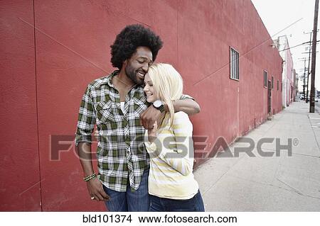 Picture - Couple hugging on urban sidewalk. Fotosearch