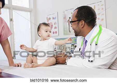 Stock Photograph - Doctor and nurse examining baby in doctor's office. Fotosearch