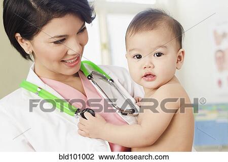 Doctor holding baby in doctor's office View Large Photo Image Stock Image - Doctor holding baby in doctor's office. Fotosearch