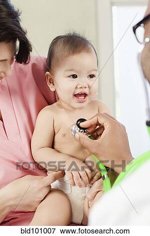 Stock Photo - Doctor listening to baby's breathing in doctor's office. Fotosearch