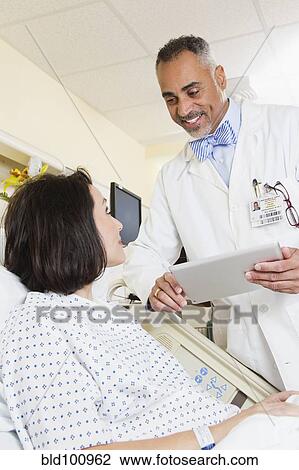 Stock Image - Doctor talking to patient in hospital. Fotosearch